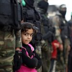 دختری فلسطینی کنار شبه نظامیان فلسطینی حماس در روز ۲۷ ژانویه ایستاده است.